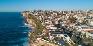 Australia’s Home Prices Predicted to Rise +10% in 2021 Aerial view of residential area across rock cliff area in Sydney coastline