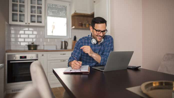Young,Smiling,Businessman,Working,From,Home,Writing,Notes,In,Notebook