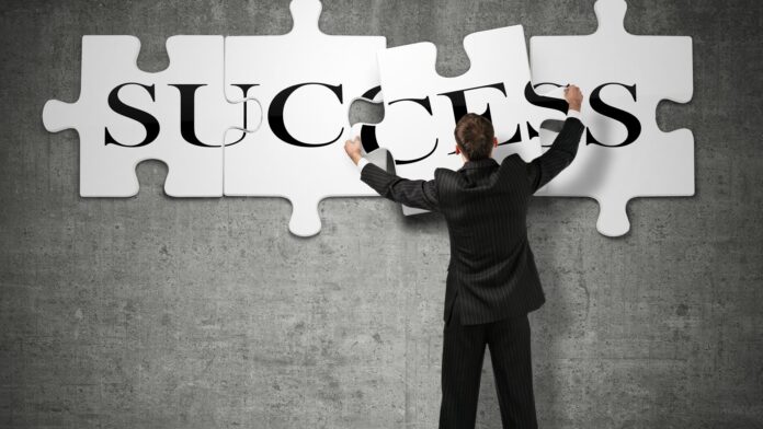 Businessman,Making,A,Puzzle,On,The,Wall,With,The,Word