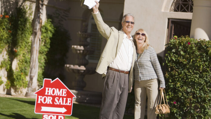 Excited,Couple,Standing,In,Front,Of,House,With,A,For