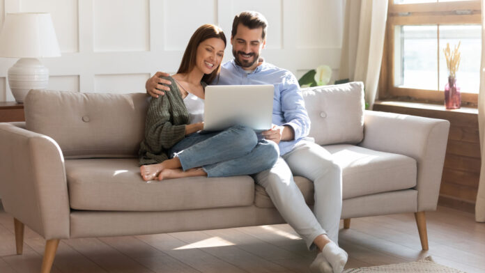 Happy,Young,Caucasian,Couple,Renters,Relax,On,Sofa,In,Living