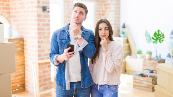 Beautiful,Young,Couple,Moving,To,A,New,House,Using,Smartphone