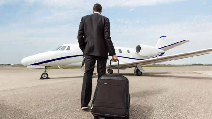Rear,View,Of,Businessman,With,Luggage,Walking,Towards,Corporate,Jet