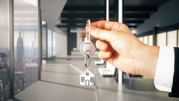 Businessman,Hand,Holding,Key,With,House,Keychain,In,Modern,Black