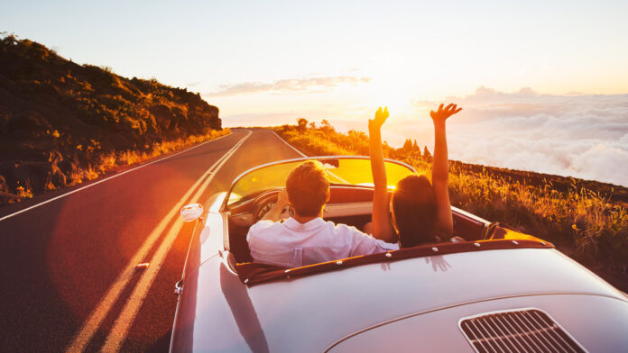 Happy,Couple,Driving,On,Country,Road,Into,The,Sunset,In