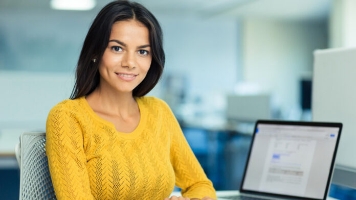 Portrait,Of,A,Happy,Casual,Businesswoman,In,Sweater,Sitting,At