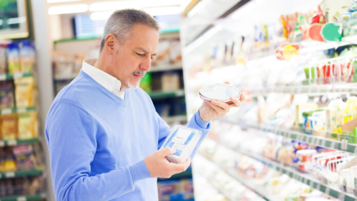 Man,Comparing,Products,At,The,Supermarket