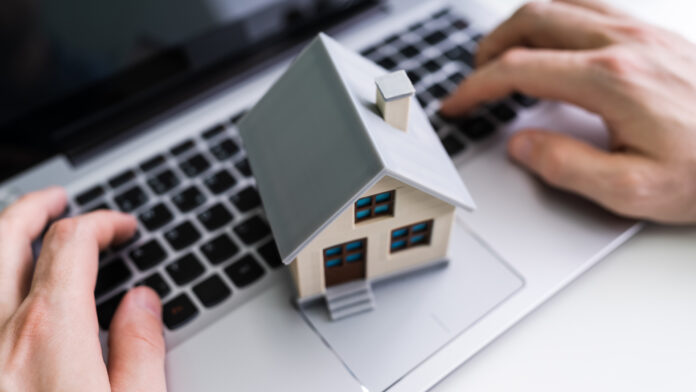 Real,Estate,House,Model,Near,Laptop,On,Desk