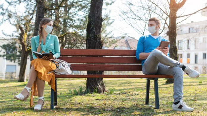 Woman,And,Man,In,Social,Distancing,Sitting,On,Bench,In